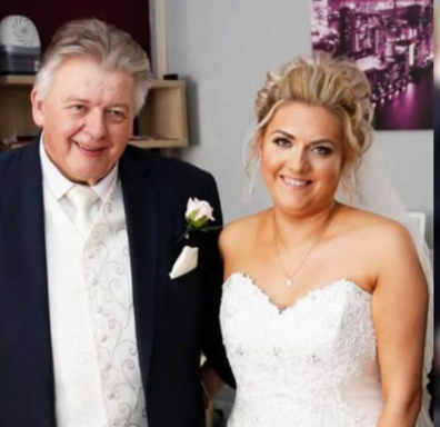 A bride in a wedding dress poses with a man in a suit, both smiling.
