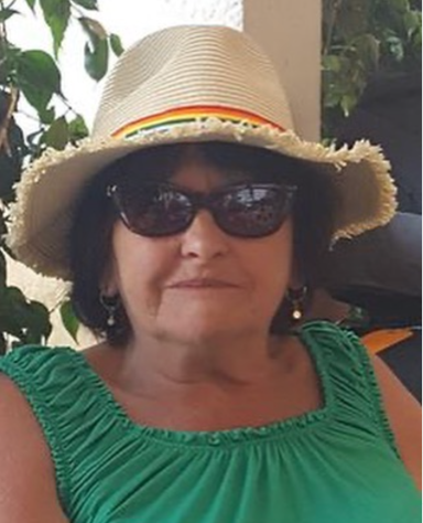 Woman with sunglasses and a wide-brimmed hat, sitting in a relaxed setting.