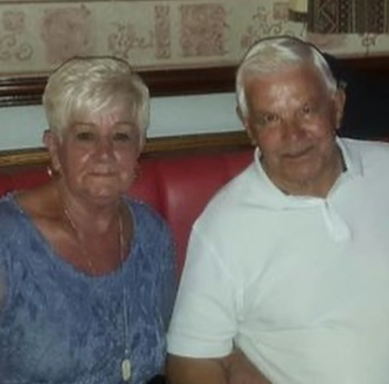 An older couple sitting together in a restaurant booth, smiling warmly.