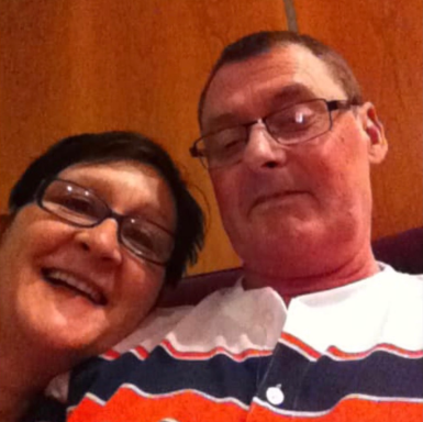 A man and woman smiling together, seated in a casual setting.