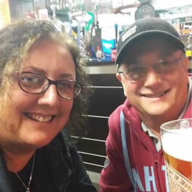 Two people smiling, posing together in a pub with a pint of beer in the foreground.