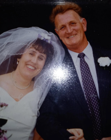 A smiling couple on their wedding day, wearing formal attire and a veil.