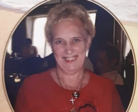 Smiling woman with short blonde hair, wearing a red top and necklace.